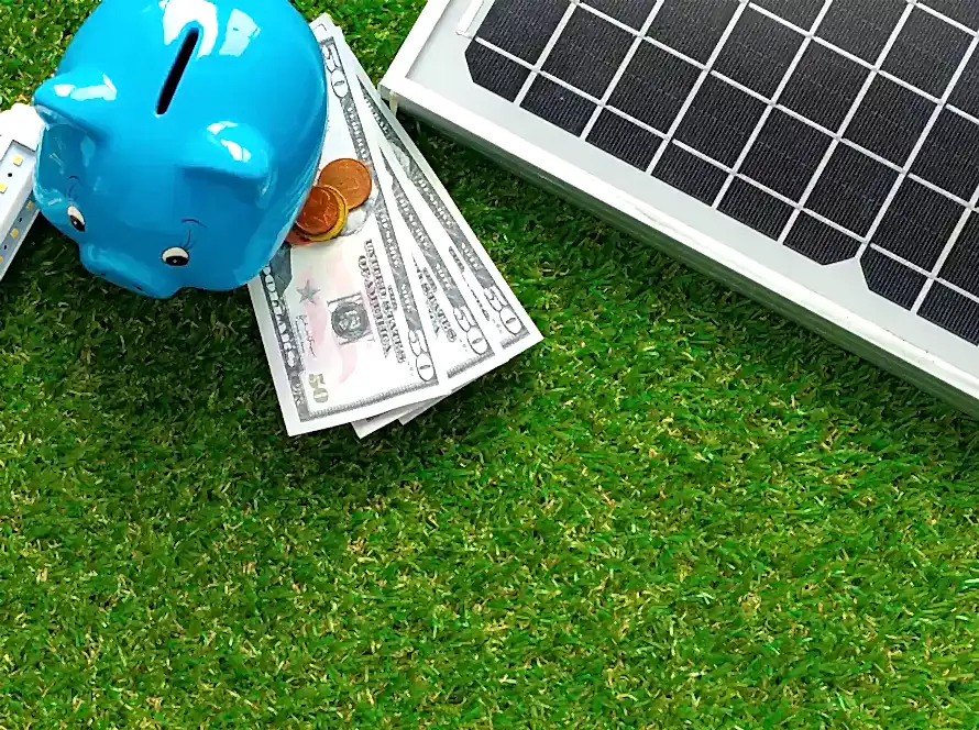 Yakın plan güneş paneli maketi ve kumbara, güneş paneli fiyatlarının akıllı yatırım fırsatını simgeliyor.